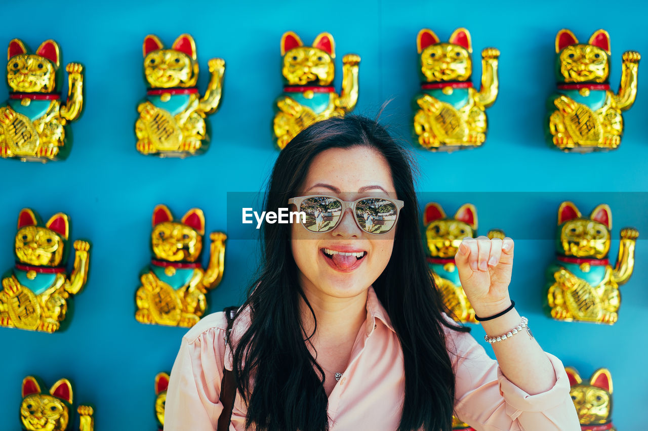 Close-up of woman wearing sunglasses against maneki neko