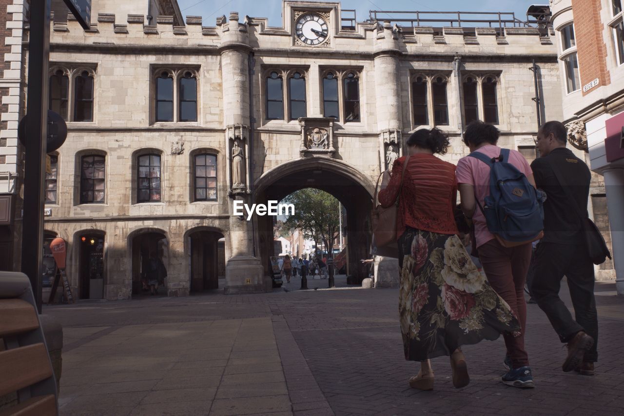 Rear view full length of people walking towards guildhall and stonebow in city