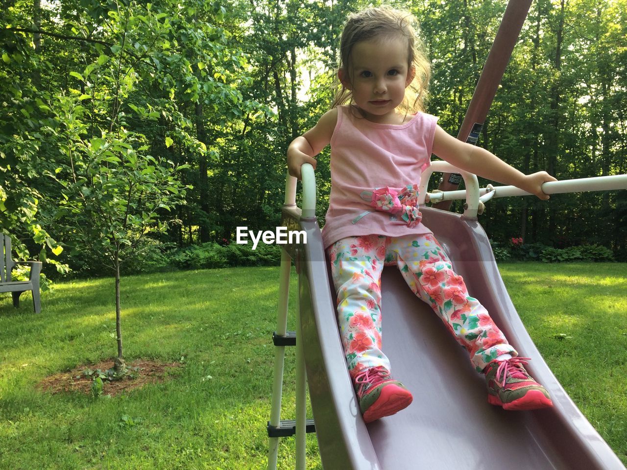 Portrait of girl sitting on slide in playground