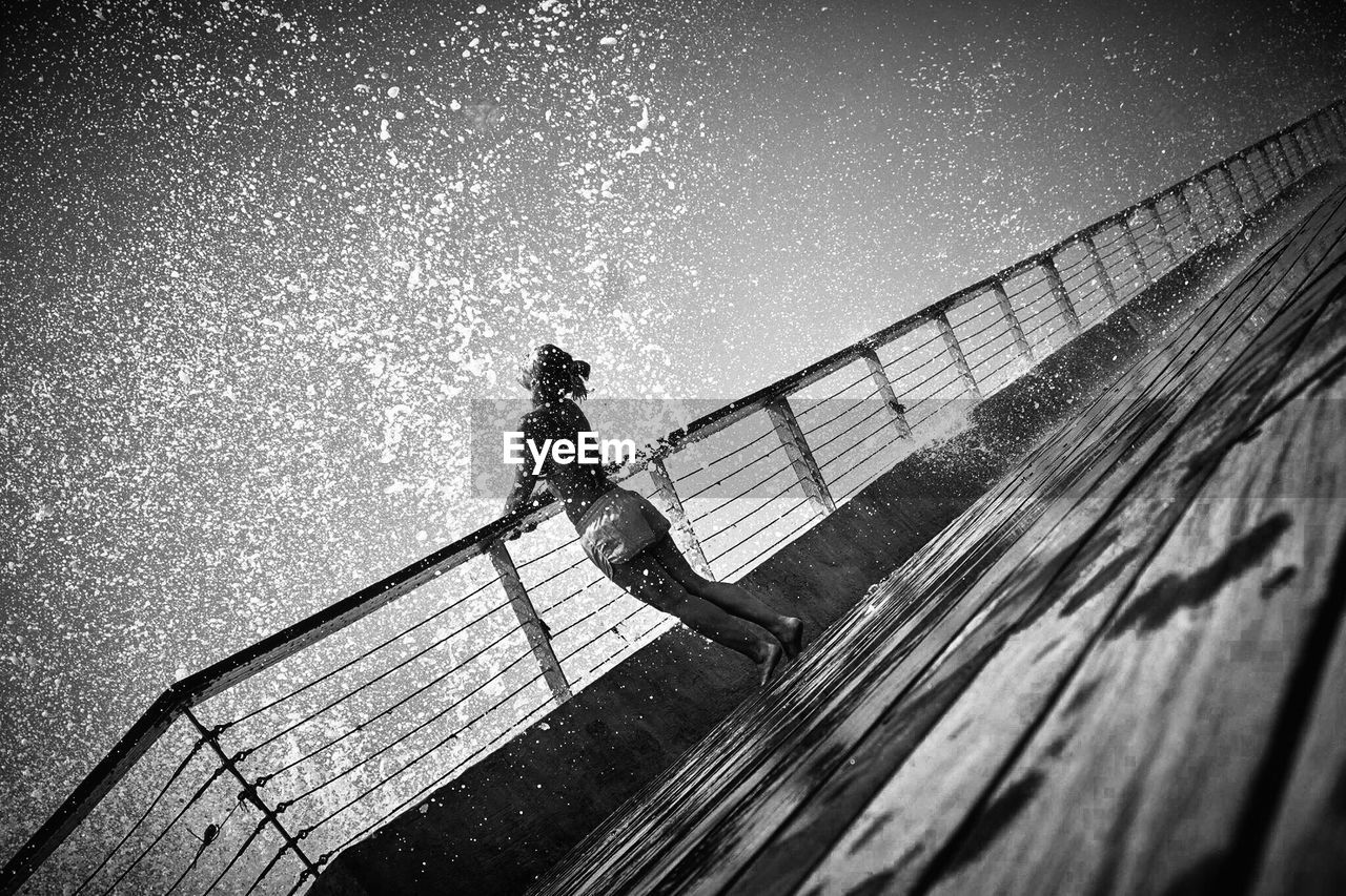 Woman enjoying water splash while standing on boat deck