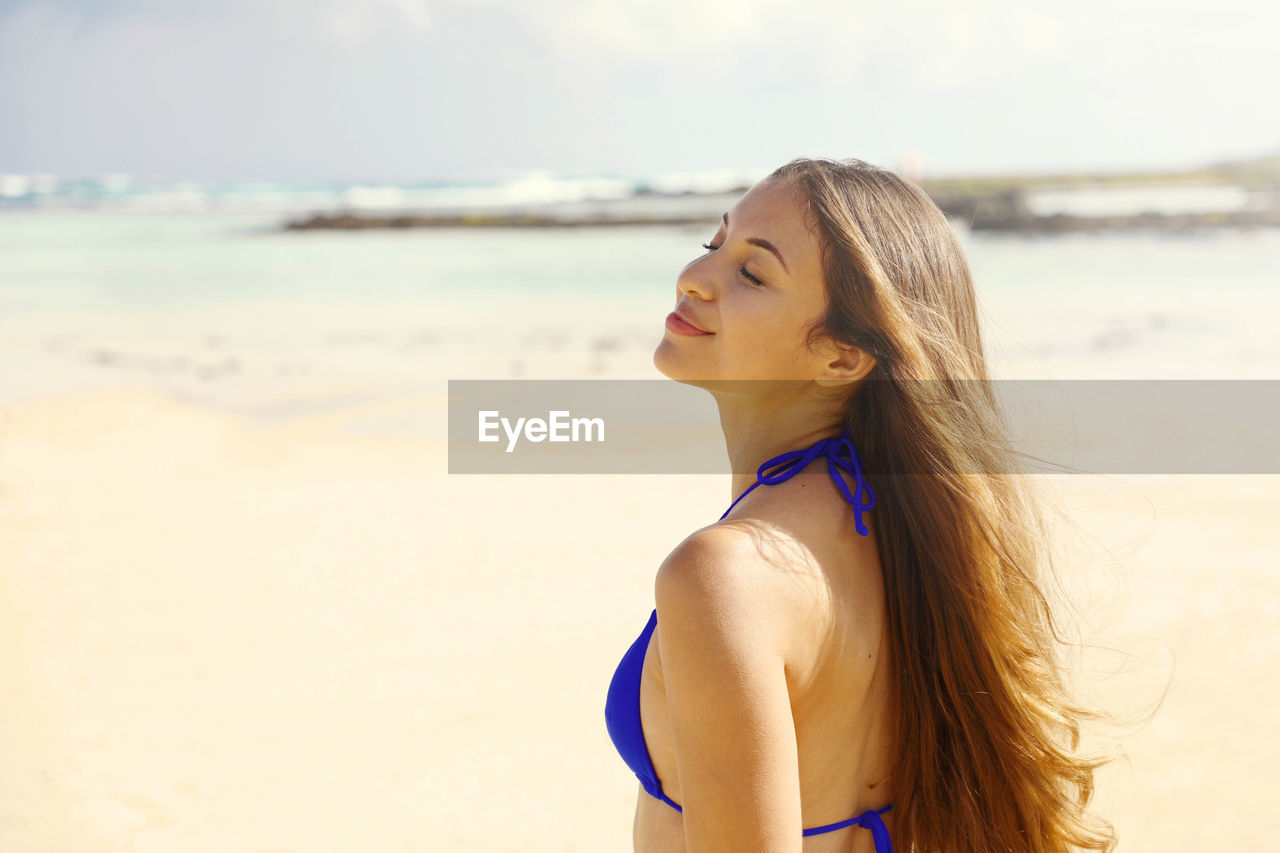 Woman with eyes closed standing at beach