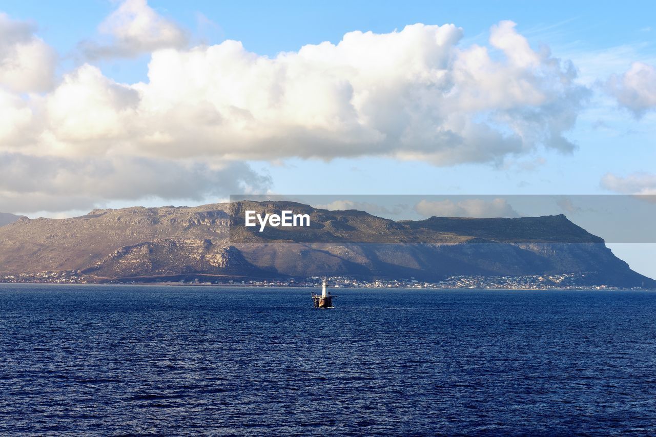 Scenic view of sea by mountains against sky