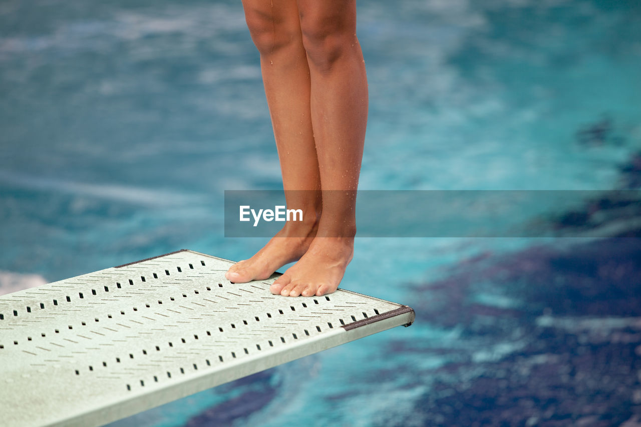 Low section of woman standing on diving board