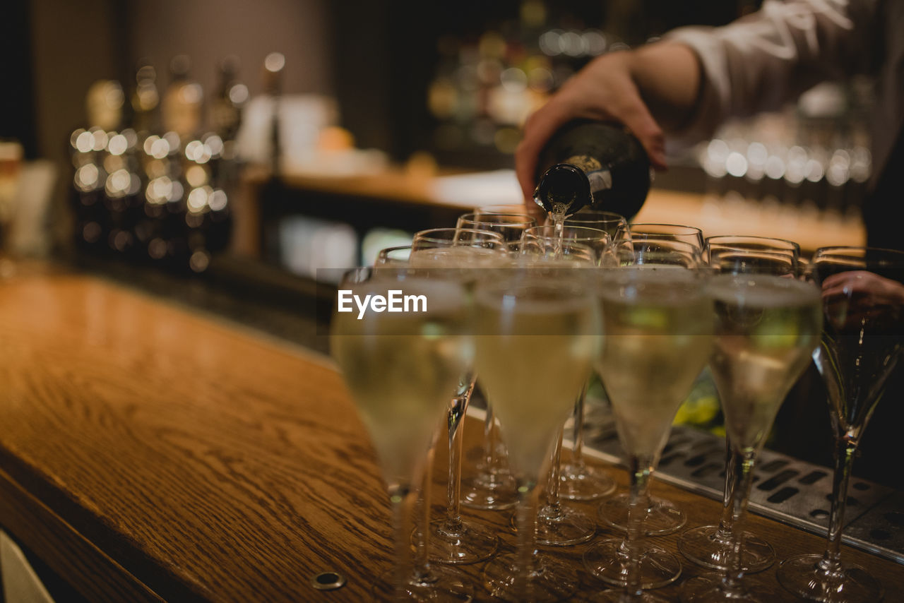 Cropped image of bartender pouring wine in glasses on counter