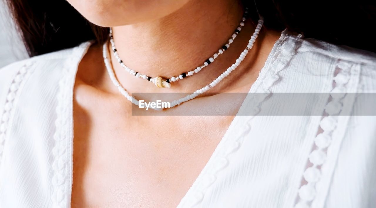 Brunette girl in a white lace blouse and a beaded and shell jewelry on her neck