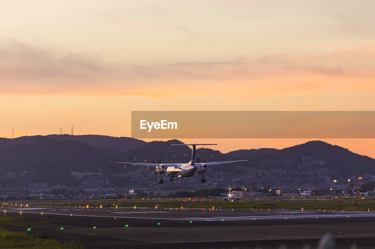 AIRPLANE ON RUNWAY AGAINST SKY IN CITY