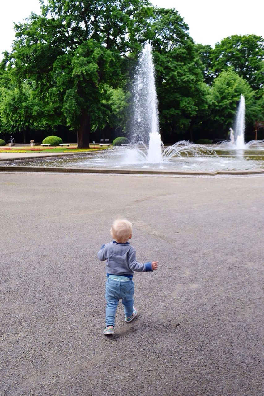 Rear view of toddler running towards fountain in tierpark berlin