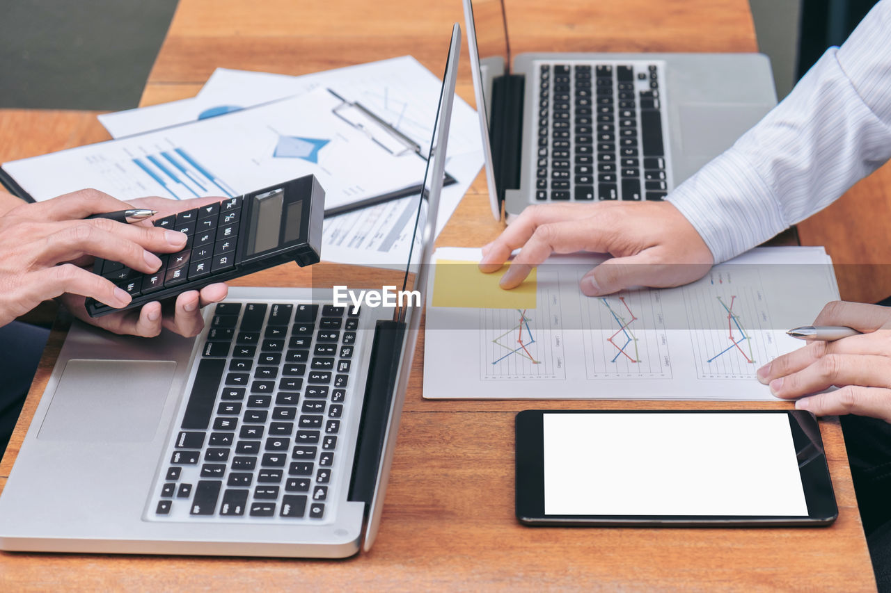 Cropped image of colleagues working at desk in office