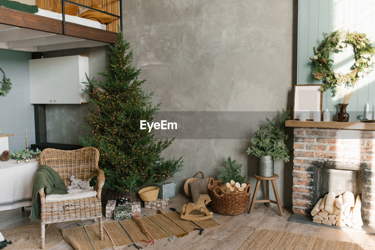 The interior of a country house with a fireplace, a christmas tree, a wicker chair and decor 