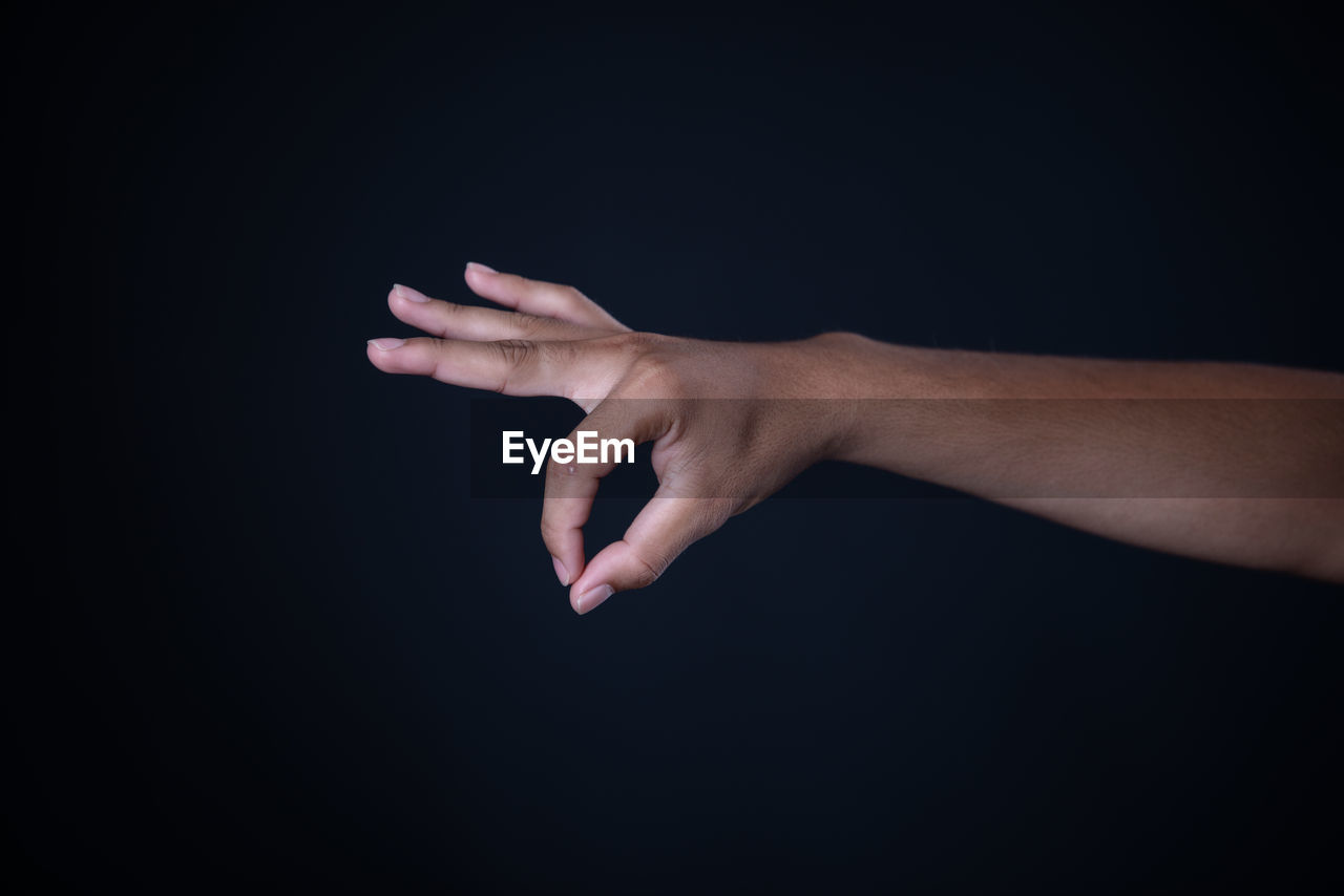 CLOSE-UP OF HAND AGAINST BLACK BACKGROUND