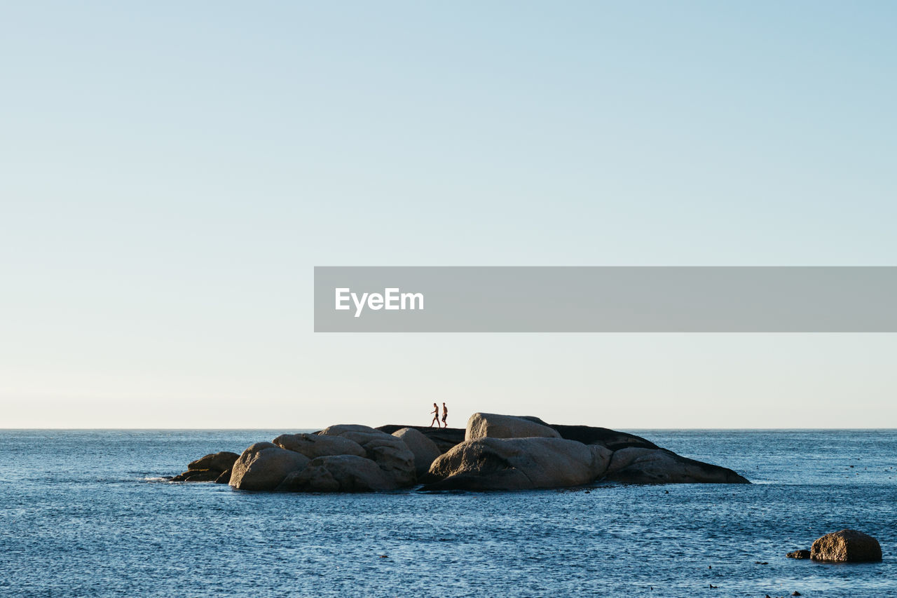 SCENIC VIEW OF ROCKS IN SEA AGAINST CLEAR SKY