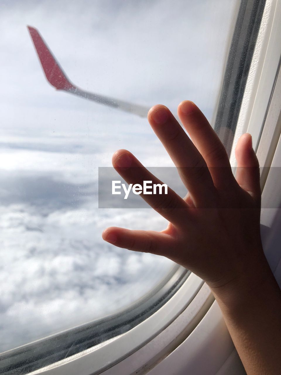 Cropped hand of child touching airplane window