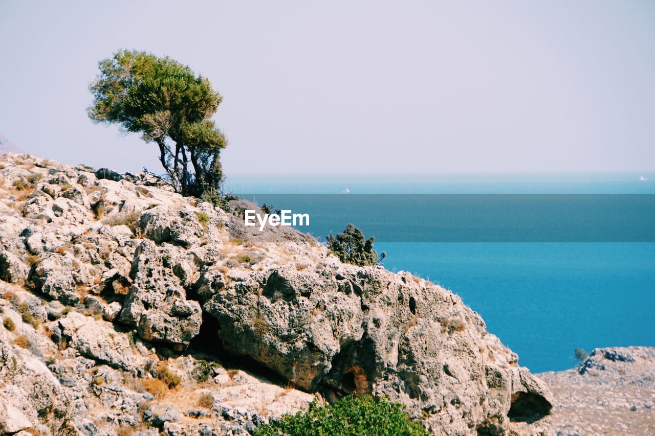 Rocks by sea against clear sky