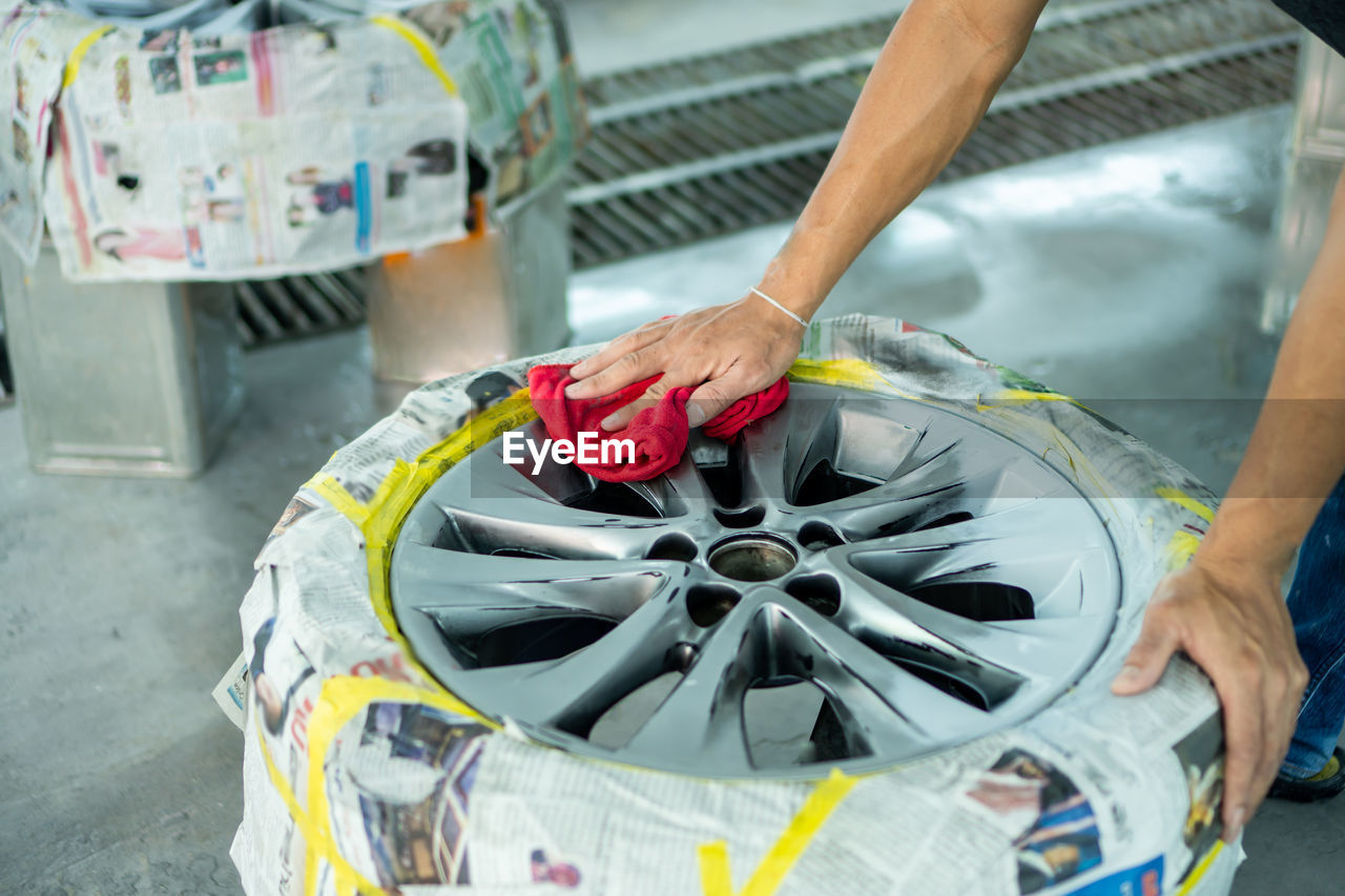 Cropped hand of worker cleaning tire at workshop