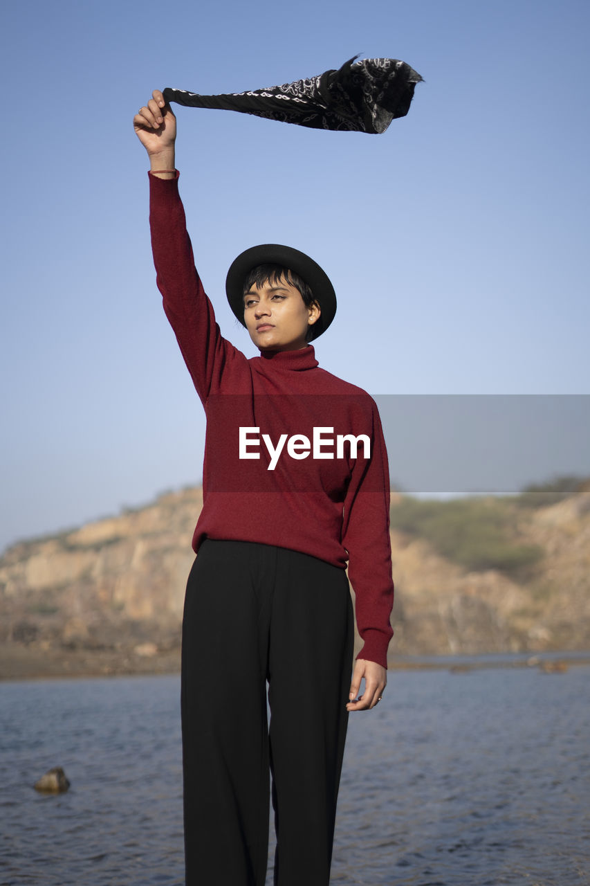 Young beautiful girl standing near a lake in the mountains with holding a hanky on her hand.