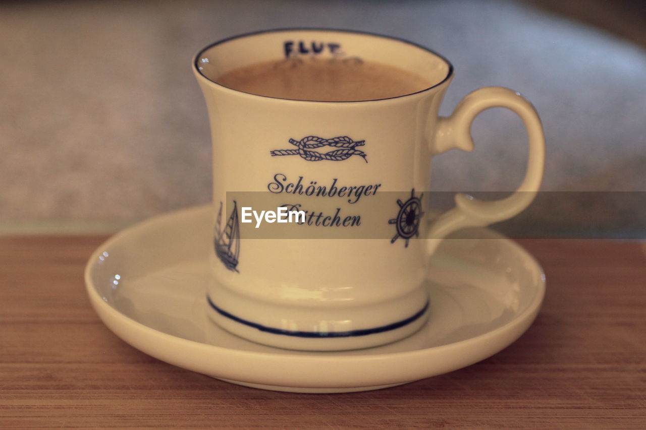 CLOSE-UP OF COFFEE CUP ON TABLE WITH TEXT