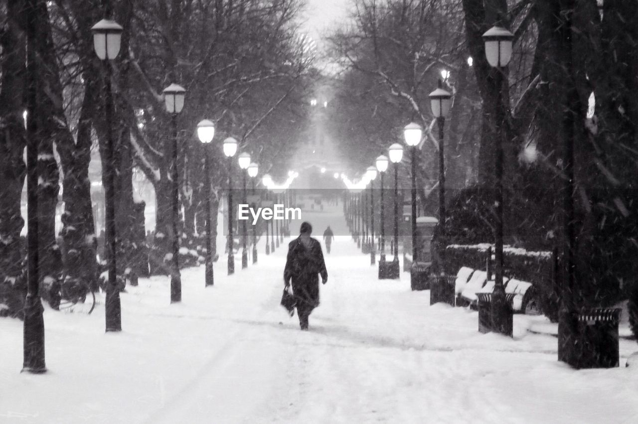 Person walking on snow covered street at dusk