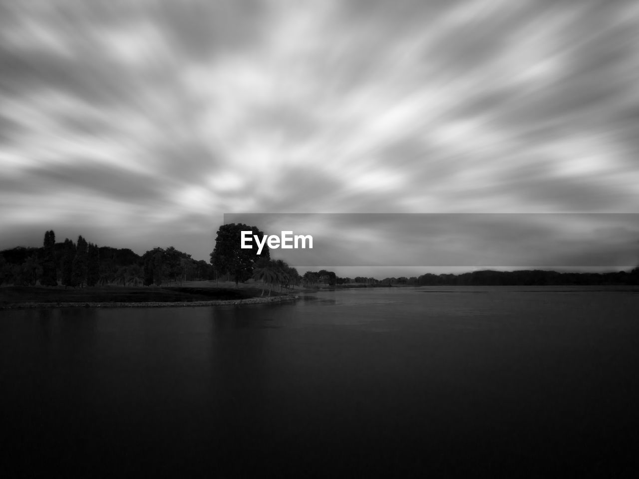 Calm lake against cloudy sky