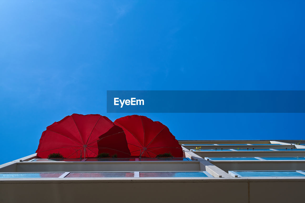 Directly below shot of red umbrella against blue sky