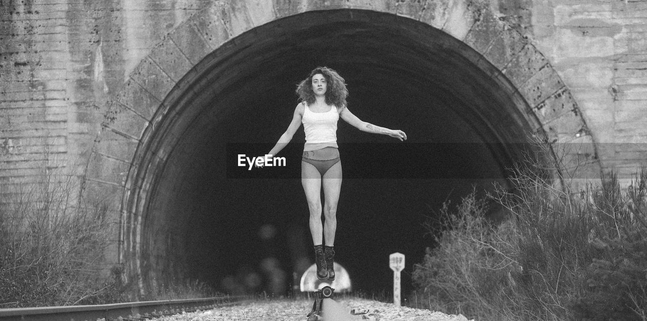 Portrait of woman levitating over railroad track