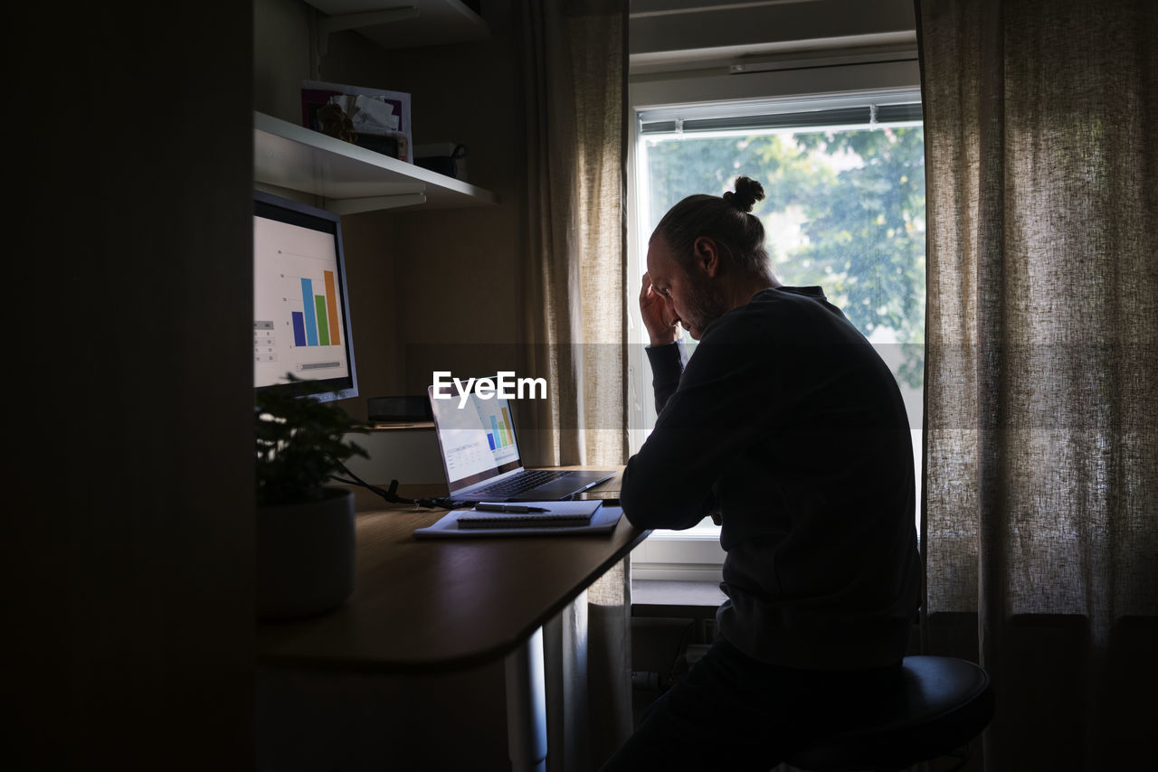 Silhouette of man using laptop at home