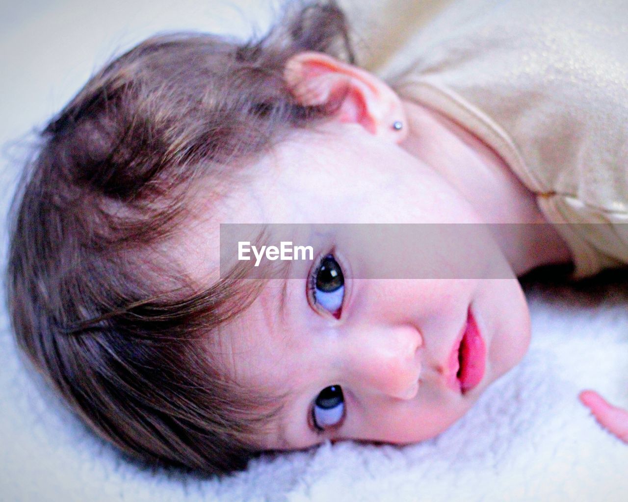 Portrait of cute baby girl lying on bed