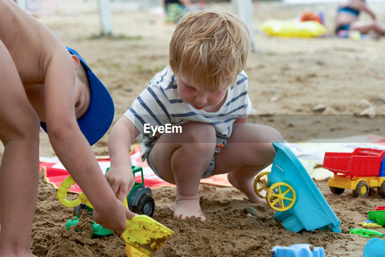 rear view of boy playing with sand at beach