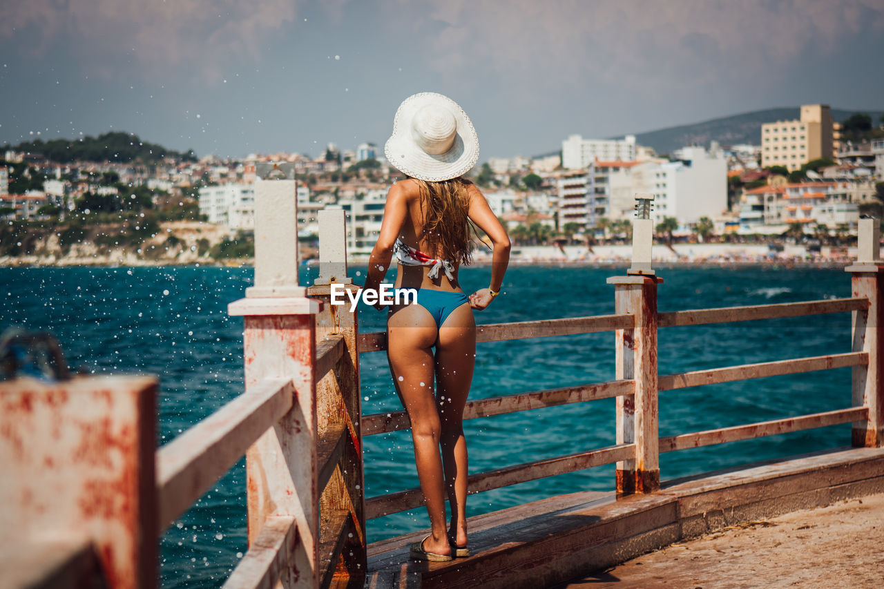 Rear view of woman wearing bikini while looking at sea