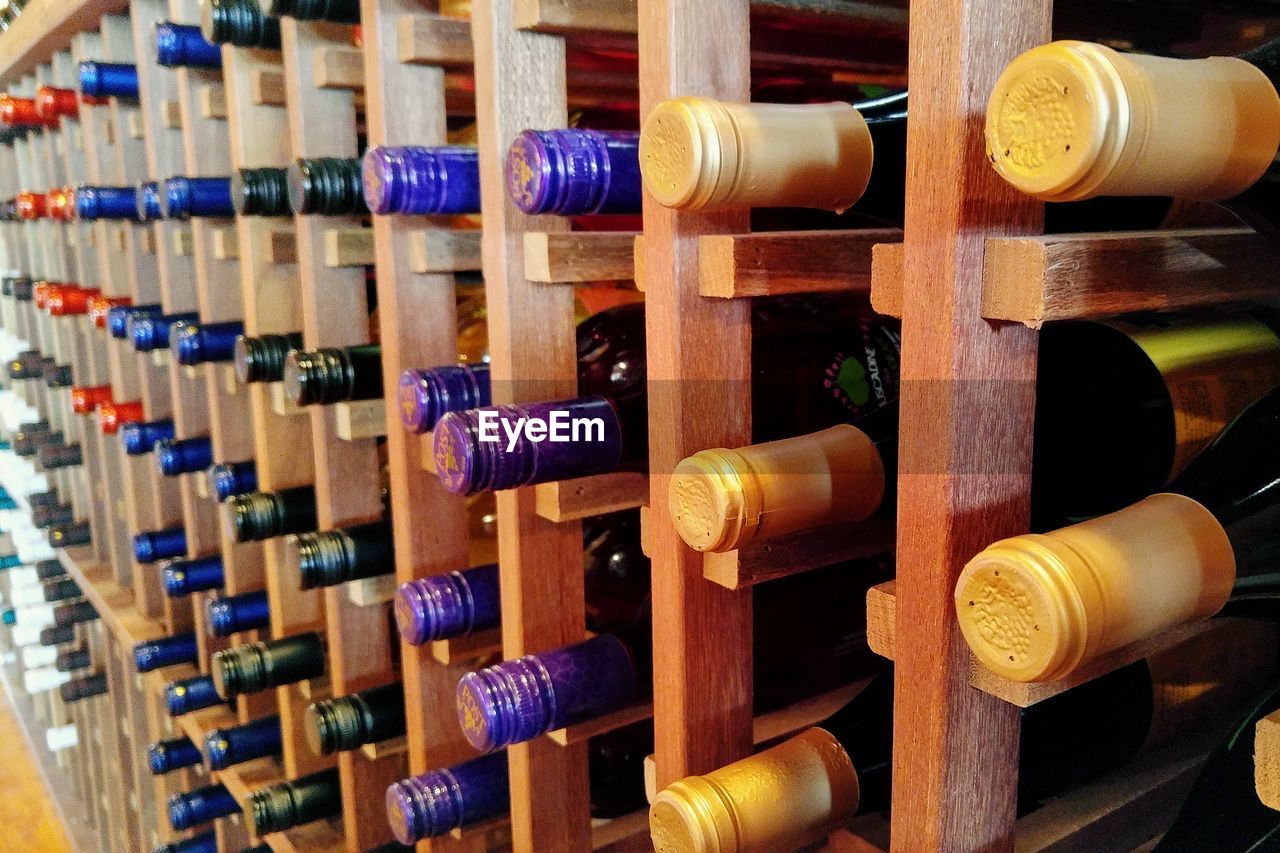 Close-up of wine bottles on wooden rack at warehouse