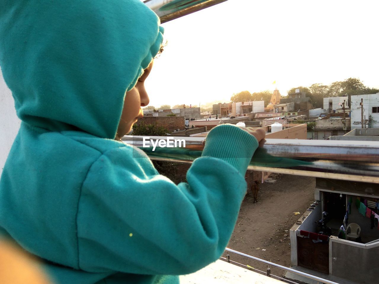 Close-up of girl looking through window against sky