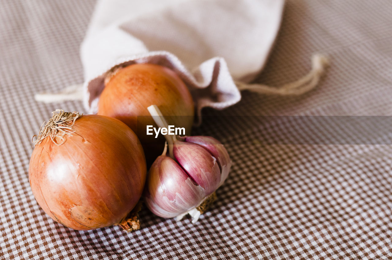 High angle view of onions and garlic in container on table