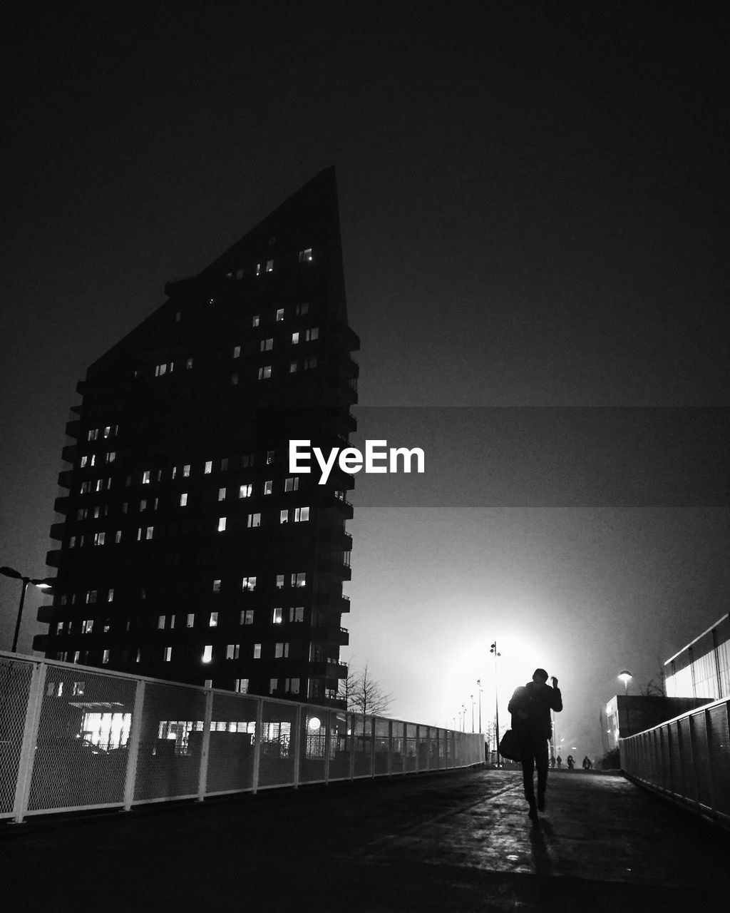 MAN WALKING ON ILLUMINATED BUILDING