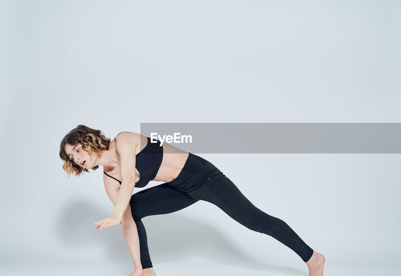 Full length of woman exercising against white background