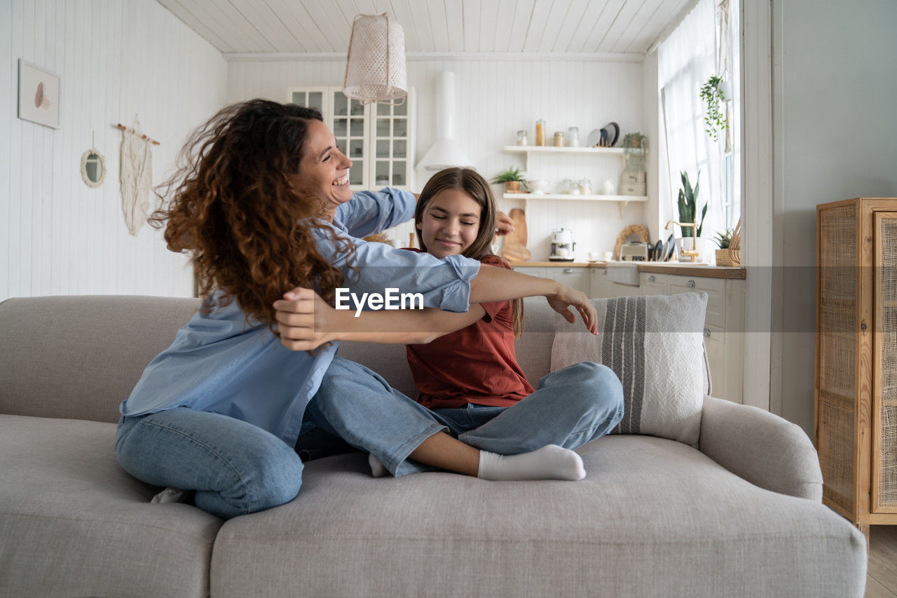 young woman using laptop while sitting on sofa at home