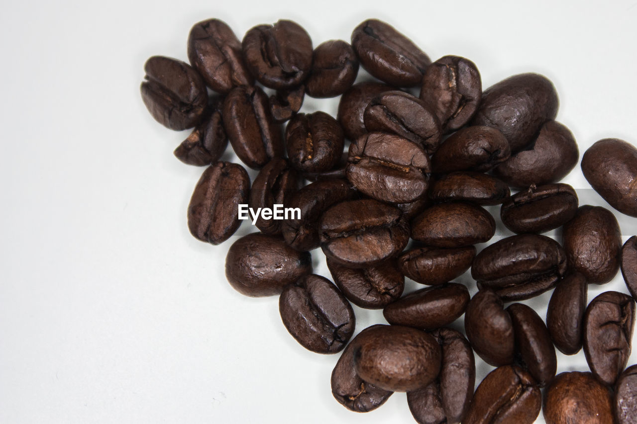 HIGH ANGLE VIEW OF COFFEE BEANS ON WHITE TABLE