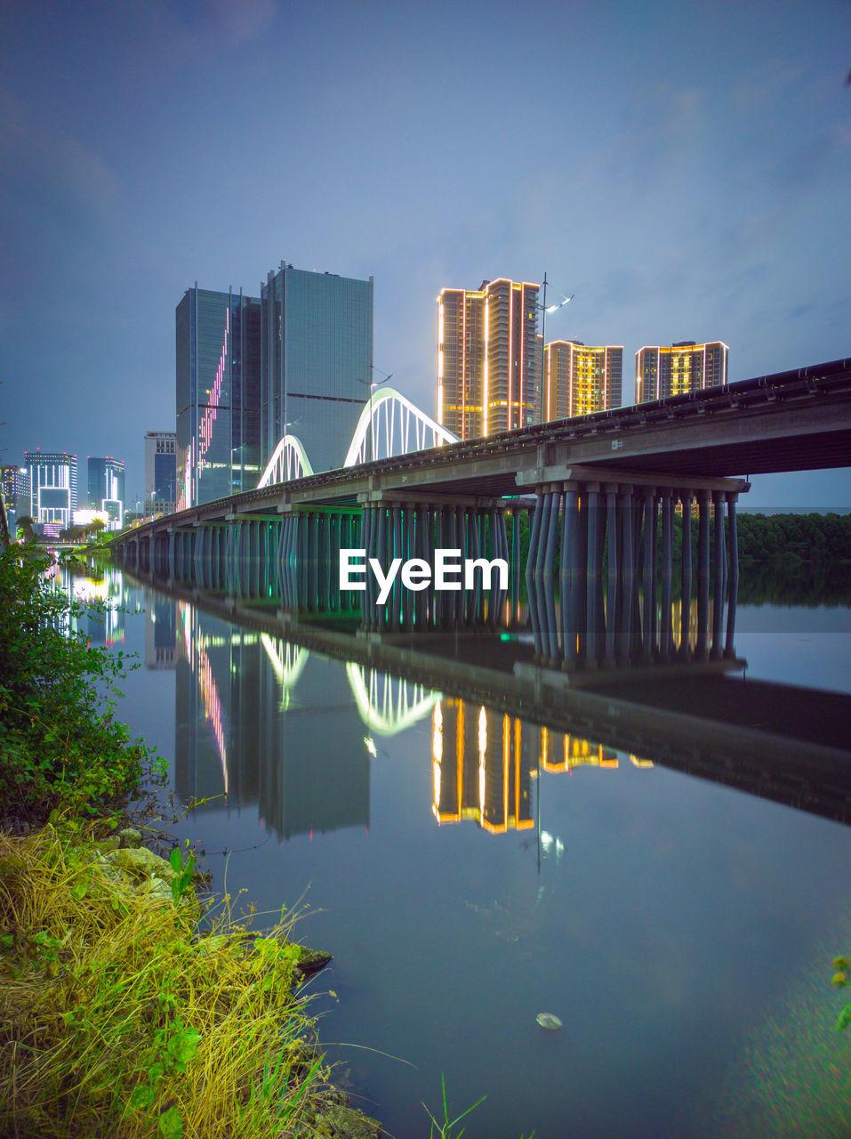 Reflection of buildings in river against sky in city