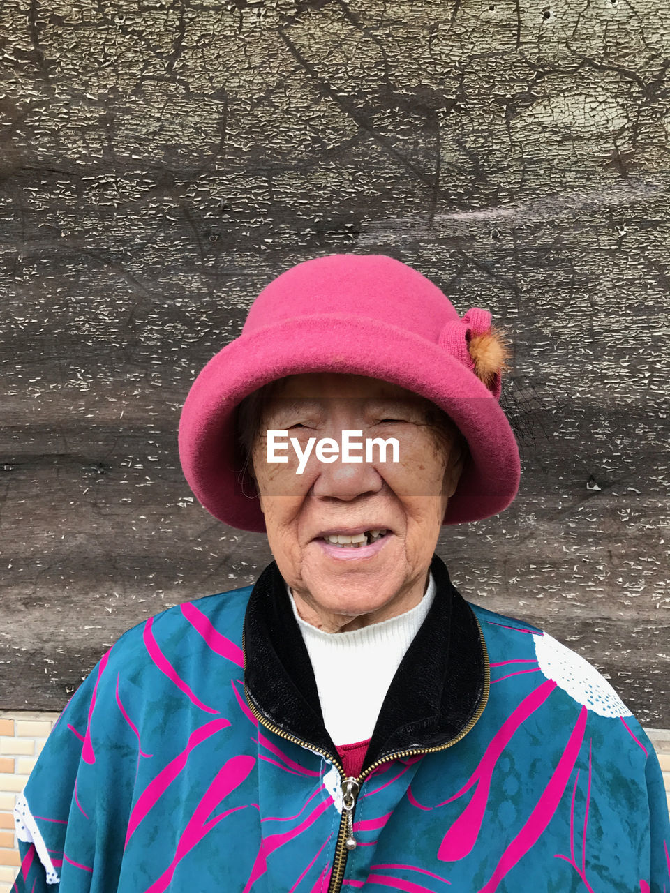 Portrait of senior woman against weathered wall