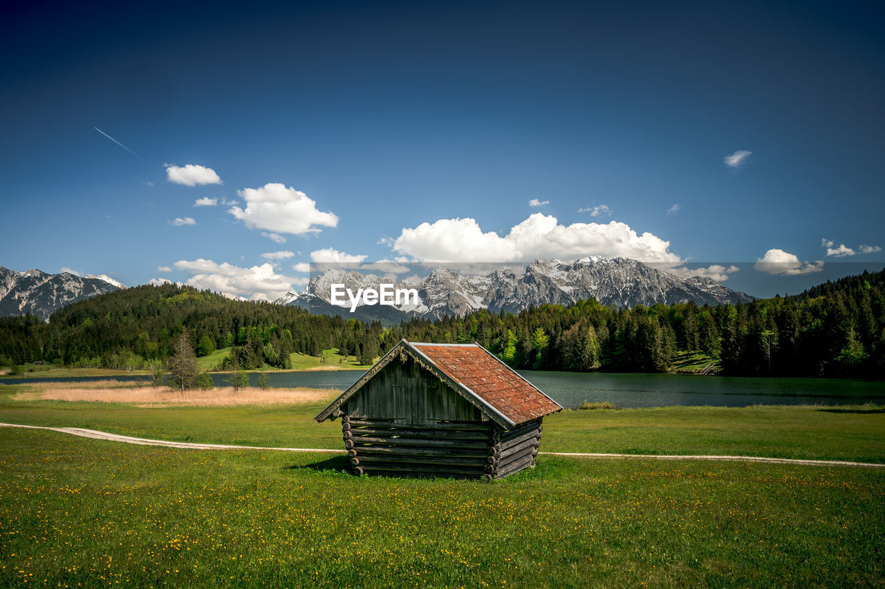 Wooden house on field against sky