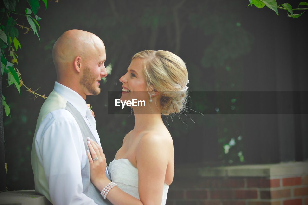 Side view of young couple looking each other face to face while standing outdoors