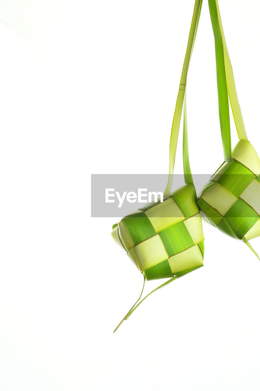 Close-up of ketupat made from coconut leaf against white background