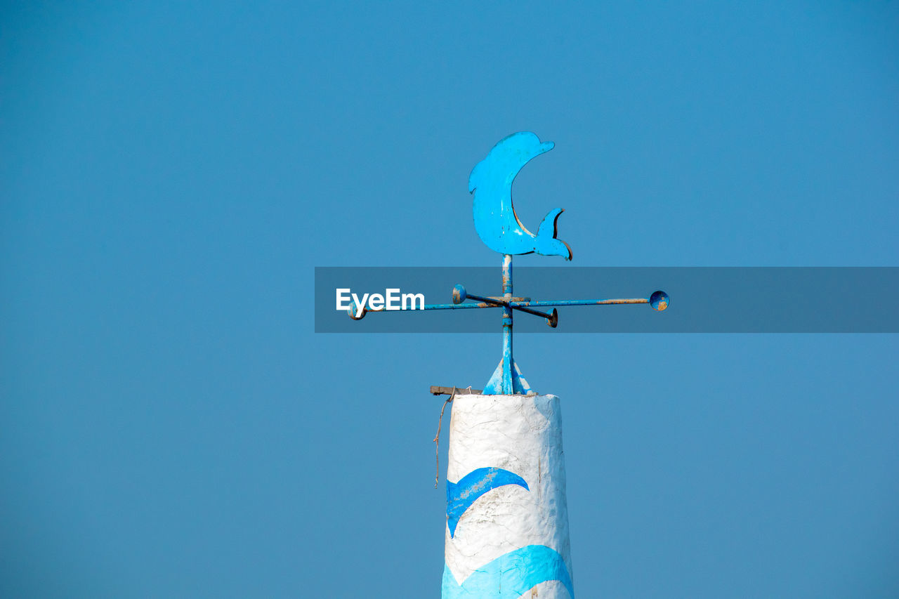 Low angle view of weather vane against blue sky