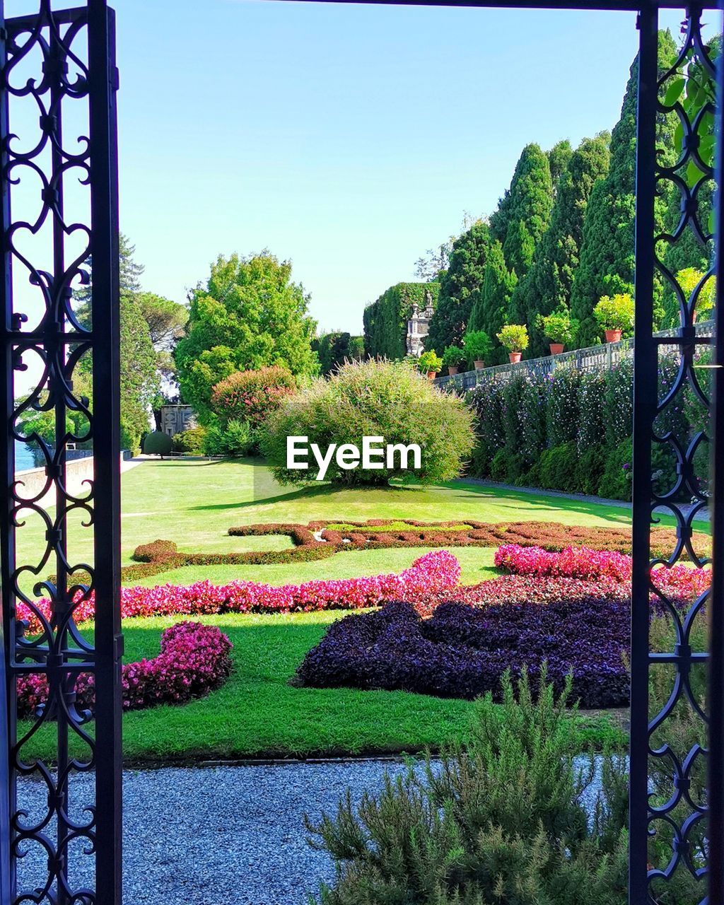 plant, nature, flower, garden, flowering plant, beauty in nature, tree, formal garden, green, growth, no people, sky, grass, day, ornamental garden, tranquility, architecture, multi colored, outdoors, scenics - nature, flowerbed, gate, lawn, park, tranquil scene, front or back yard, blue, clear sky, park - man made space, built structure, sunlight, backyard