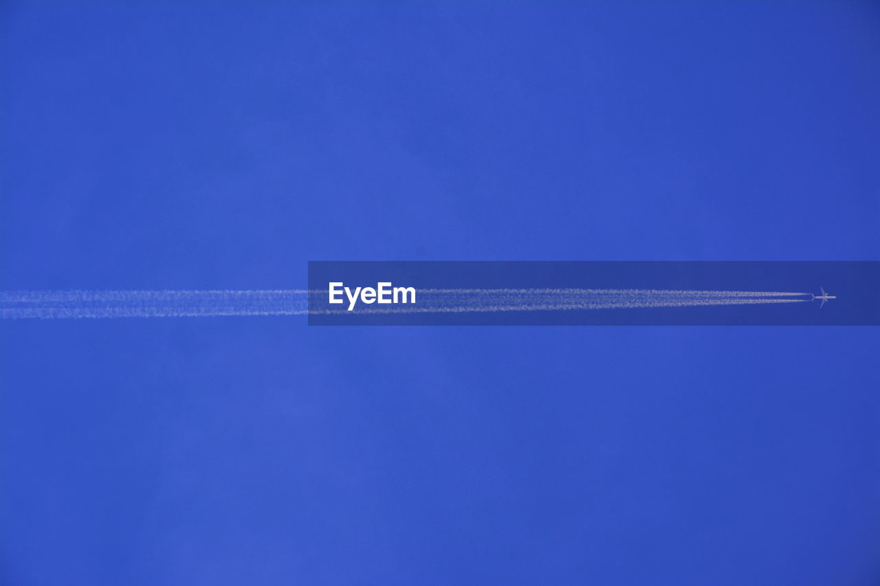 Airplane with vapor trail in blue sky