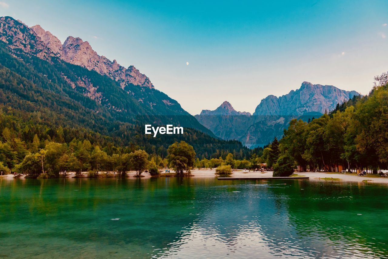 Scenic view of lake by mountains against sky