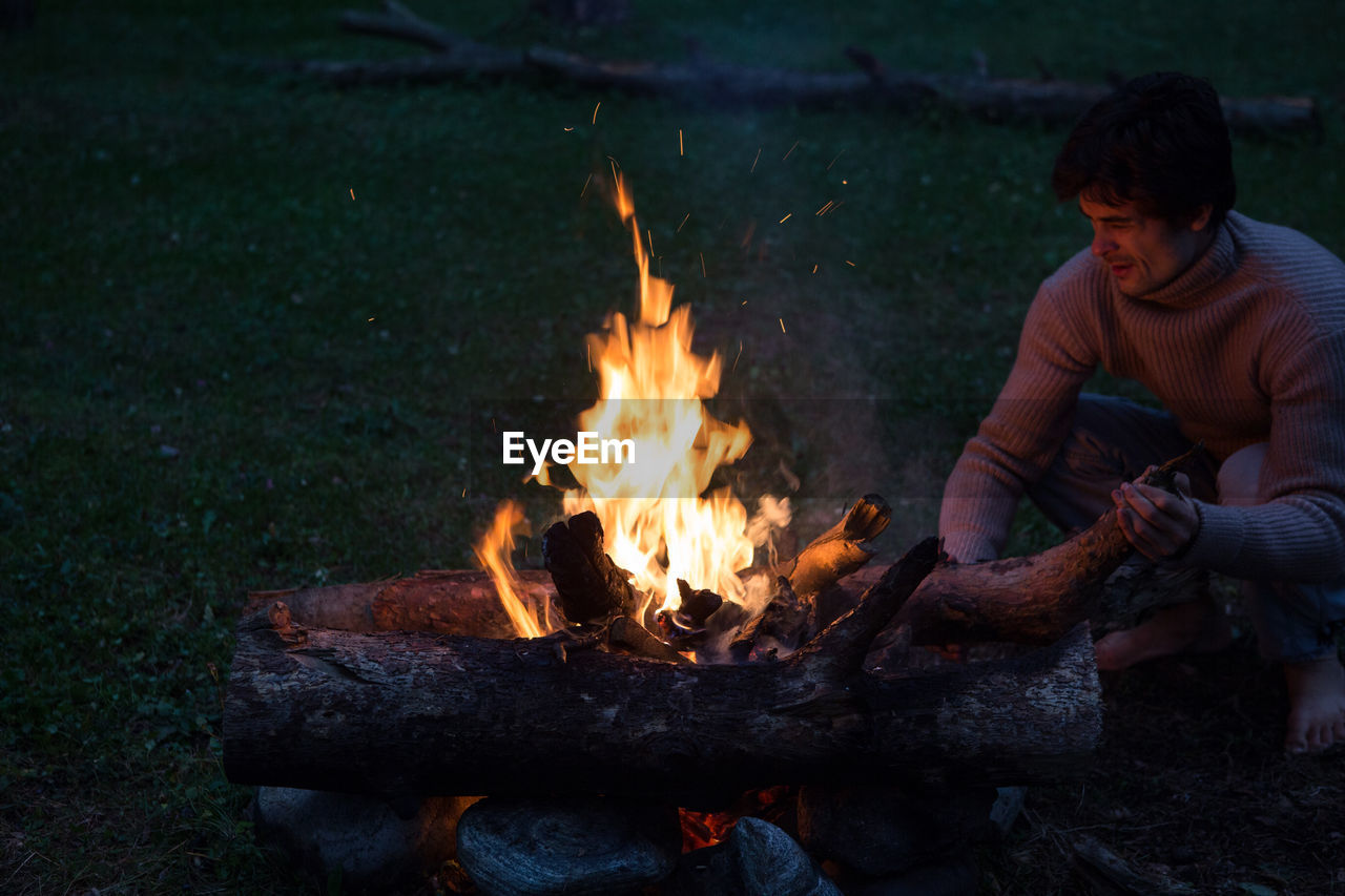 Man by campfire on field