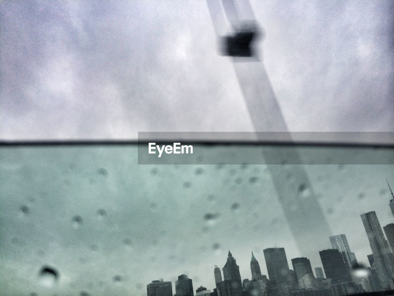 City skyline against sky seen through wet glass window