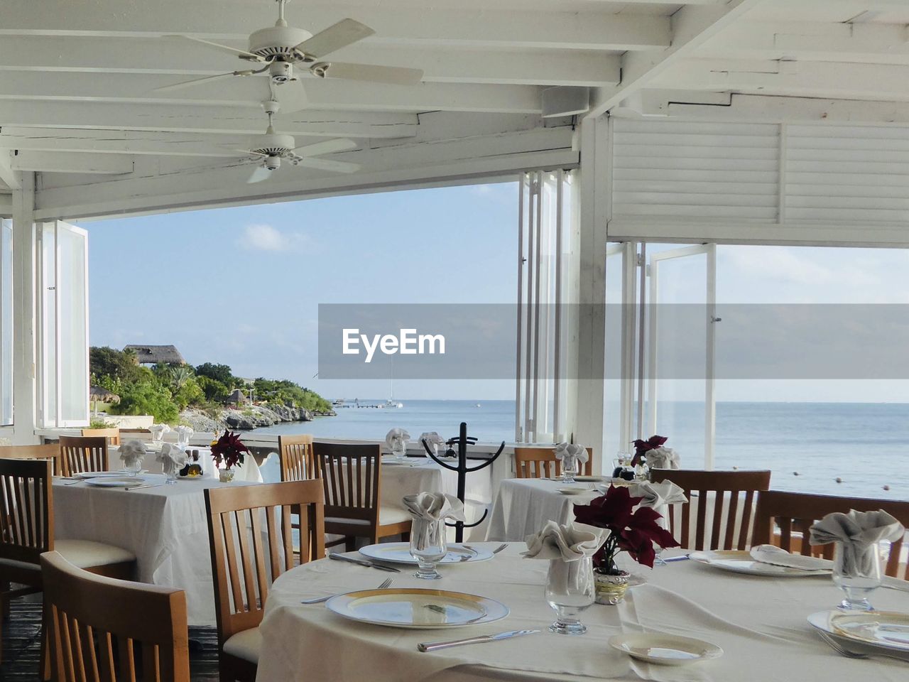 Chairs and tables at restaurant by sea against sky