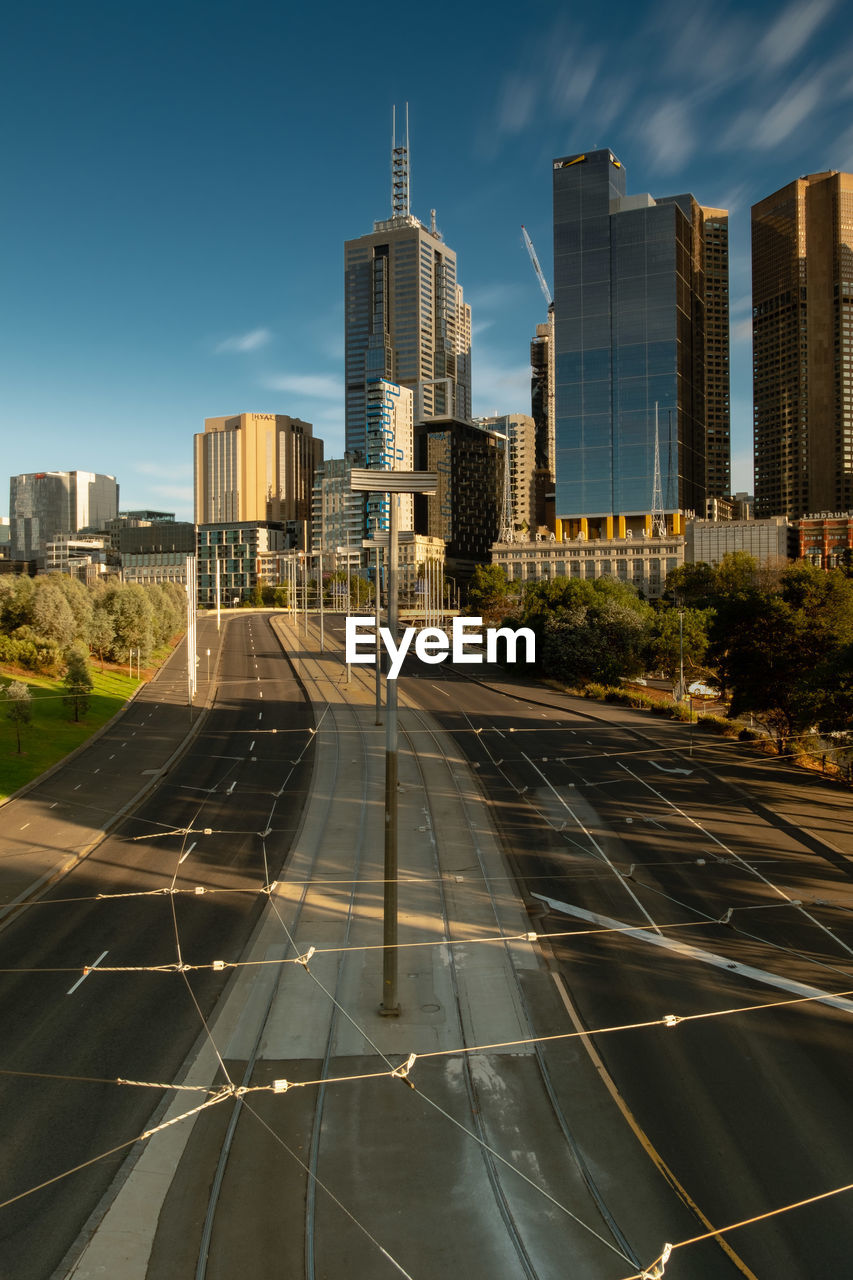 Road by buildings in city against sky