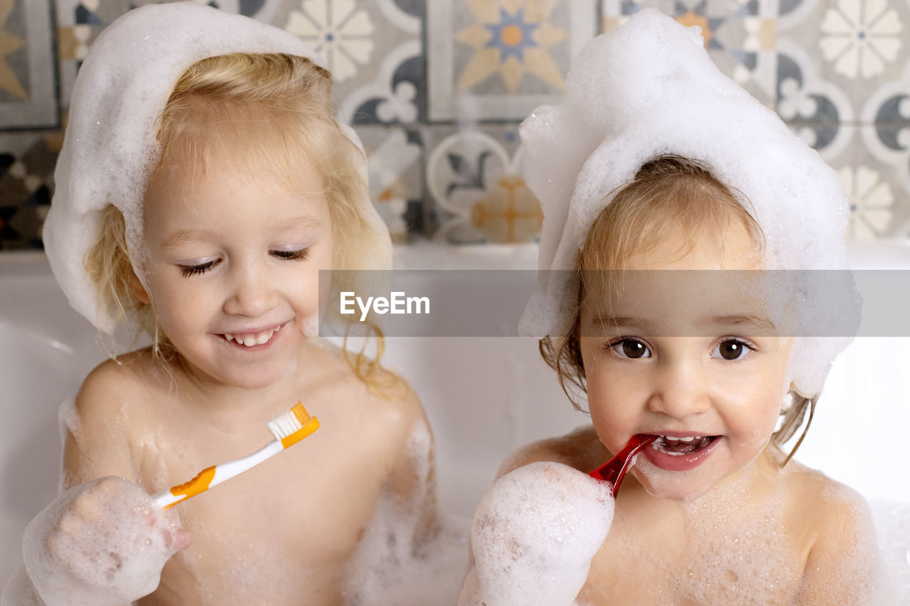 Cute girls brushing teeth in bathtub