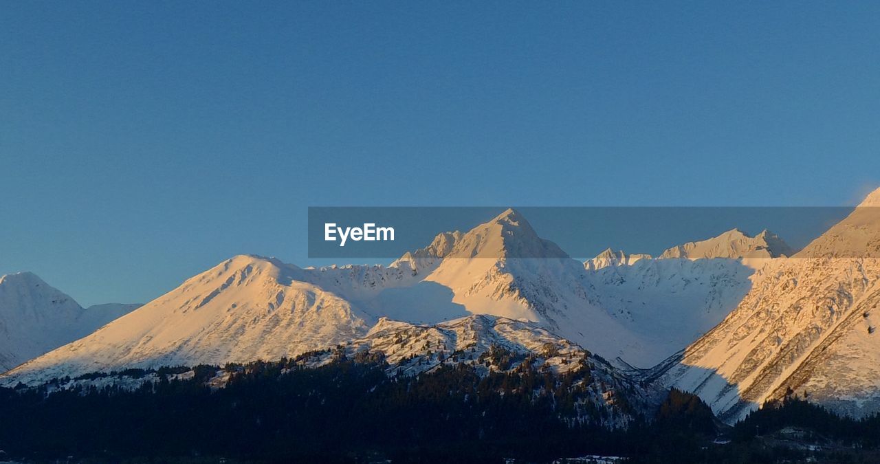 Scenic view of snowcapped mountains against clear blue sky